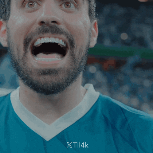 a man with a beard is wearing a blue shirt that says xtil4k on the bottom