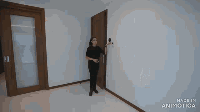 a woman in a black shirt is pressing a button on a wall