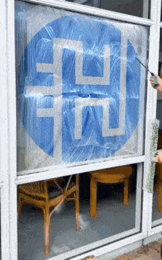 a person is cleaning a window with a blue sign that says ' ec ' on it