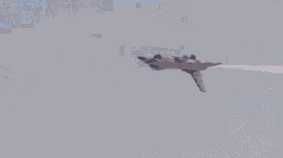 a fighter jet is flying through the air in front of a mountain .