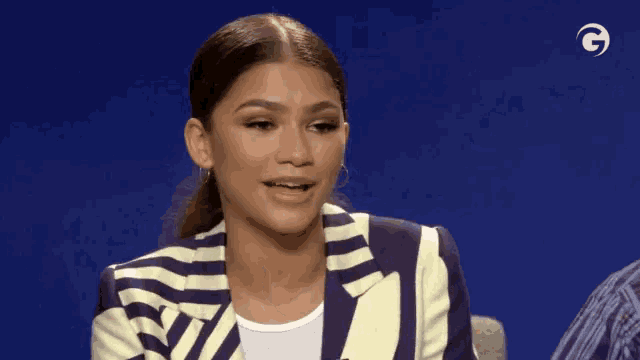 a woman is wearing a striped jacket and making a funny face .