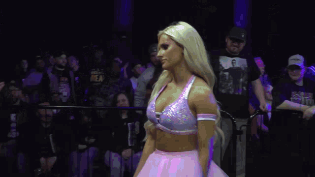 a woman in a pink tutu is standing in front of a crowd wearing a ny hat