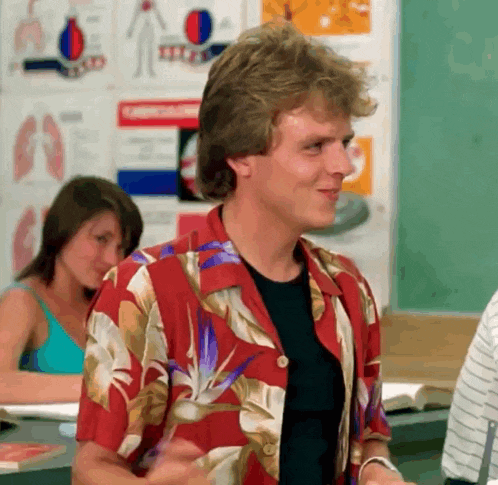 a man in a hawaiian shirt is standing in a classroom with other students