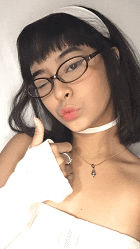 a young woman wearing glasses and a choker necklace