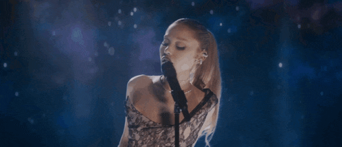 a woman singing into a microphone with a ponytail