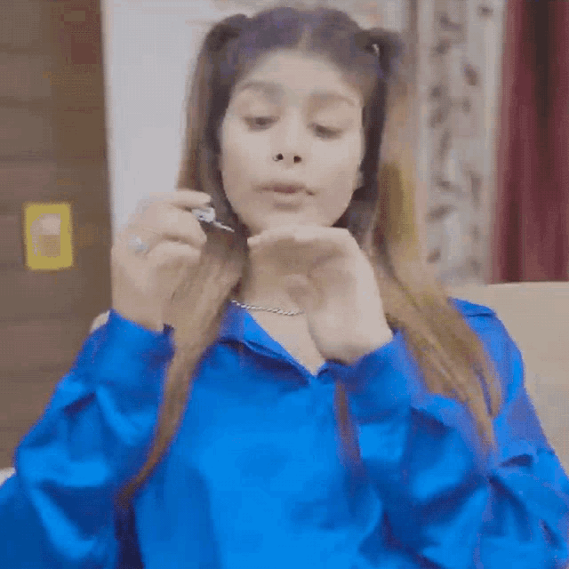 a woman in a blue shirt is holding a spoon in her hand .
