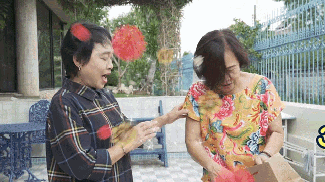 a woman in a plaid shirt and a woman in a floral shirt open a box