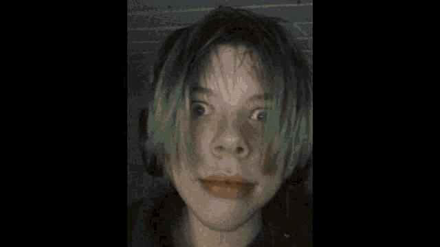 a girl with green hair looks at a toy dinosaur in the background