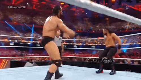 two men are wrestling in a wrestling ring with a referee .