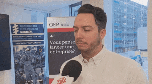 a man talking into a microphone in front of a sign that says " vous pensez lancer une entreprise "