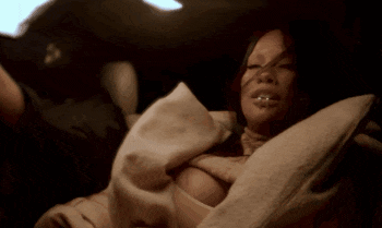 a woman is laying under a blanket in the back seat of a car .