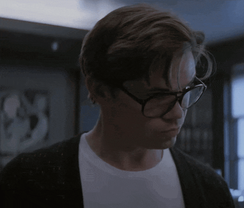 a young man wearing glasses and a black cardigan