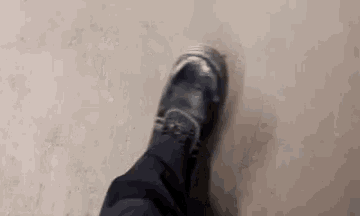 a close up of a person 's foot wearing a pair of black shoes on a concrete floor .