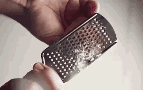 a person is grating cheese on a grater in their hands .