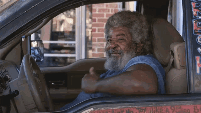 a man with a beard is sitting in the driver 's seat of a truck with a sticker that says toy