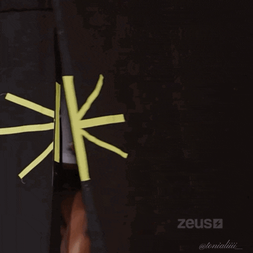 a woman in a zeus t-shirt is standing in a dark room