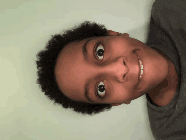 a close up of a young boy 's face with a gray shirt on