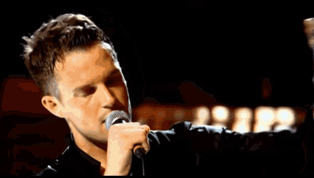 a man singing into a microphone while holding a bottle