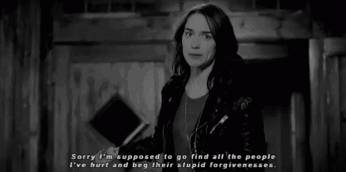 a black and white photo of a woman in a leather jacket standing in a room .