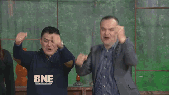 a man wearing a shirt that says bne holds his fist up in the air