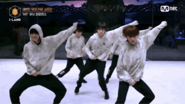 a group of young men are dancing on a stage in front of a mnet logo