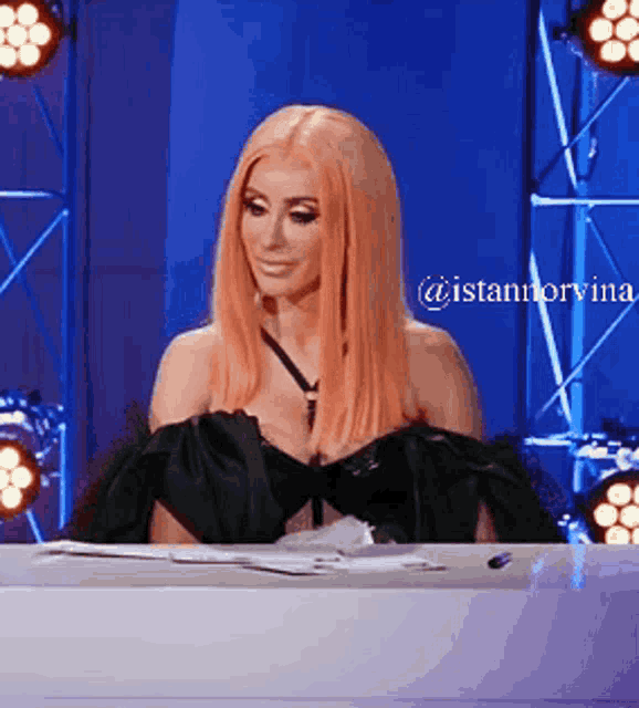 a woman in a black dress is sitting at a table with a caption that says @istannorvina