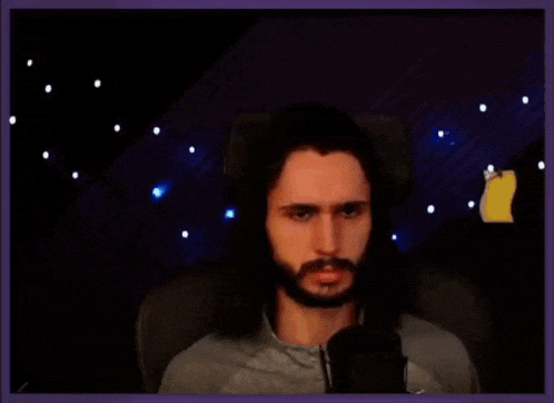 a man with long hair and a beard is sitting in front of a microphone