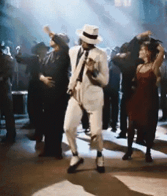 a man in a white suit is dancing in front of a crowd of people .