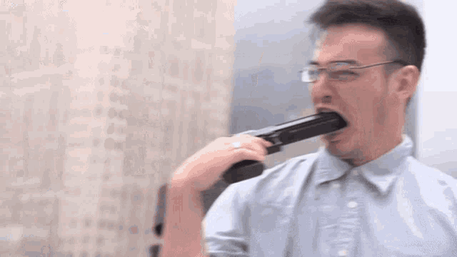 a man with glasses is holding a gun in his mouth ..