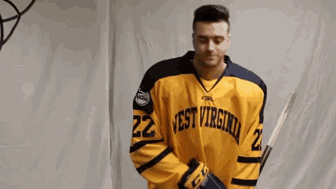 a man wearing a yellow west virginia hockey jersey