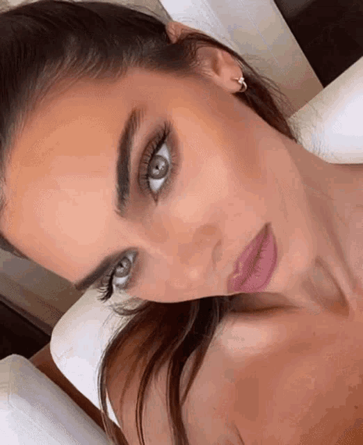 a close up of a woman 's face with long eyelashes and a pink lip .