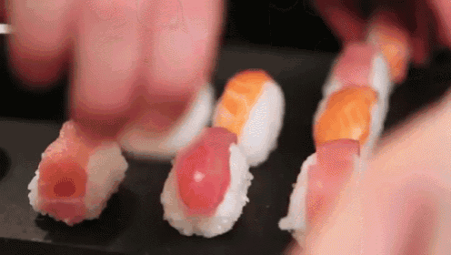 a person is making sushi with their hands on a table .