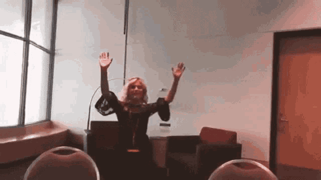 a woman stands in a room with her arms up