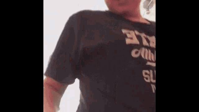 a person wearing a black t-shirt with the word supreme on it is standing in a room .