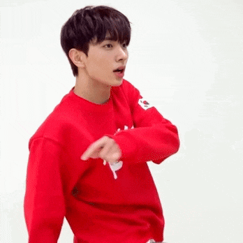 a young man wearing a red sweatshirt is making a funny face and pointing at the camera .