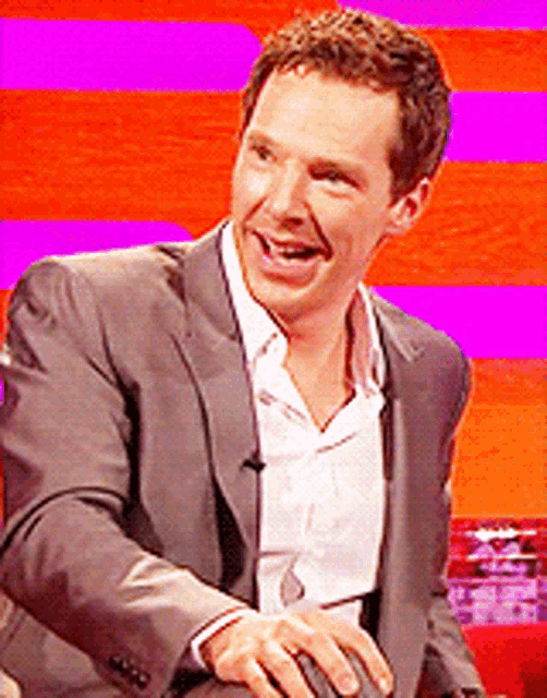 a man in a suit and white shirt is smiling and laughing