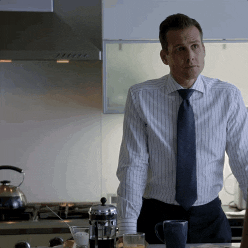 a man wearing a striped shirt and tie stands in a kitchen