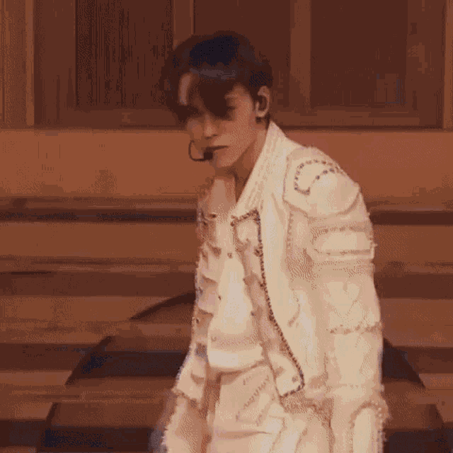 a man in a white jacket is standing in front of a microphone .