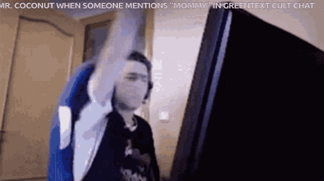 a man sitting in front of a computer with his arm in the air