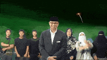 a man in a suit stands in front of a group of people .