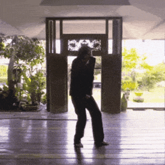 a man in a suit is dancing in front of a door