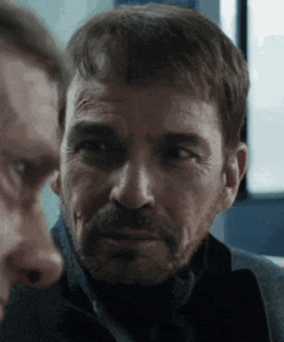 a close up of a man 's face with a beard looking at another man 's face .