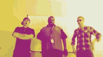 a group of three men are standing next to each other in a room .