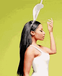 a woman wearing bunny ears is blowing a kiss while standing in front of a green background .