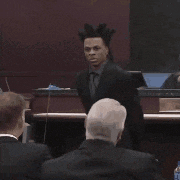 a man in a suit with dreadlocks stands in front of a podium