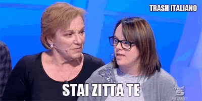 two women are standing next to each other and one of them is wearing glasses .