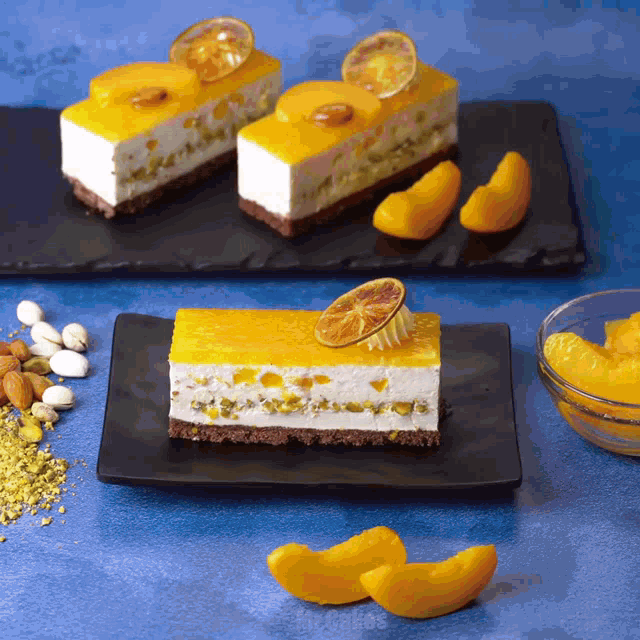 a slice of cake on a black plate next to a bowl of peaches and nuts