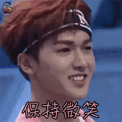 a young man wearing a headband and a pink shirt is smiling in a blurry photo .
