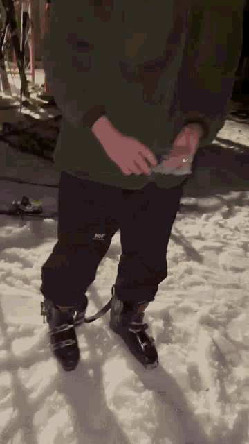 a person wearing a green sweatshirt and black pants with the letters h & m on them