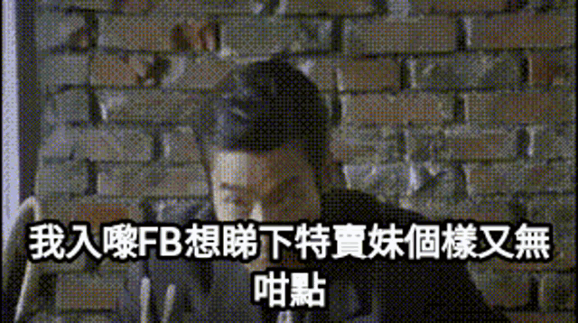 a man sitting in front of a brick wall with chinese writing on it